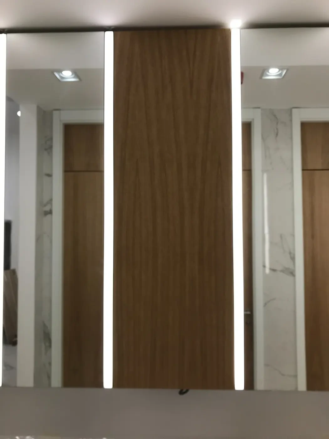 Detalj furniranog MDF panela u hrastu između ogledala sa LED rasvetom